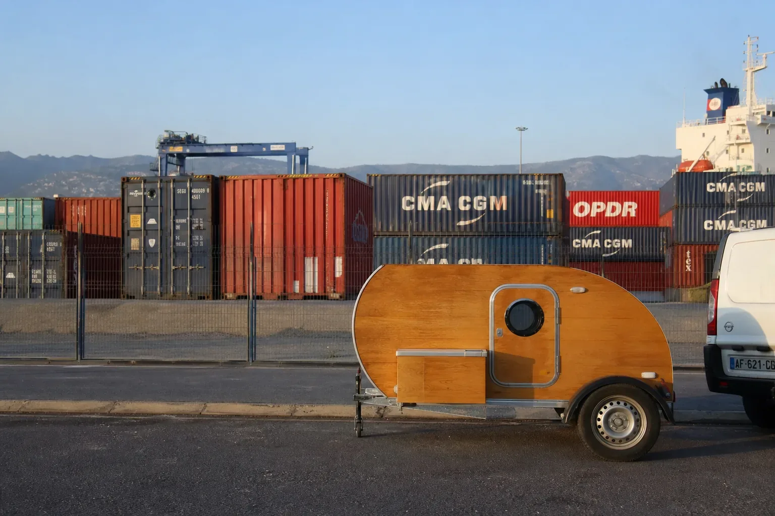 Caravane teardrop dans une zone portuaire marocaine avec containers de dédouanement