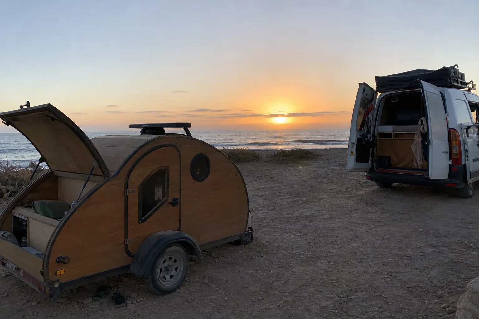 Caravane teardrop et van aménagé sur une plage atlantique marocaine au coucher du soleil